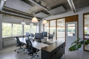 Modern kantoorinterieur aan de Anthony Fokkerweg met bureaus, computerschermen en grote ramen met uitzicht op groen.
